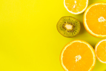 Fruit frame. Colorful fresh citrus fruits on a light green background. Orange, tangerine, lemon and kiwi are cut in half. Flat lay, top view, copy space.