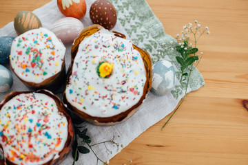 Stylish easter eggs natural dyed and homemade easter cake on rustic cloth with flowers and green brunches on wooden table. Happy Easter. Traditional Easter food. Flat lay