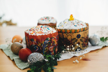 Homemade easter cake and stylish easter eggs natural dyed on rustic cloth with flowers and green brunches on wooden table. Happy Easter. Traditional Easter food. Copy space