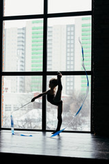 Gymnast performs an exercise with a ribbon. Silhouette of a girl