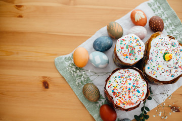 Fototapeta na wymiar Homemade easter cake and stylish easter eggs natural dyed on rustic cloth with flowers and green brunches on wooden table. Happy Easter. Traditional Easter bread. Flat lay