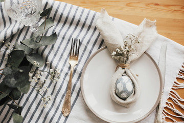 Easter table decorations. Stylish Easter brunch table setting with egg in easter bunny napkin....