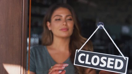 Female owner of coffee shop or restaurant walking up to door and turning round sign to open - shot in slow motion - Powered by Adobe