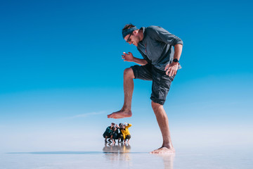 Forced perspective of young tourists at Uyuni Salt Flats (Spanish: Salar de Uyuni ) in Bolivia, South America