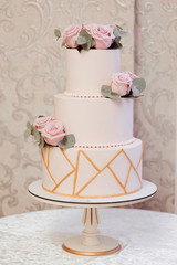 Close up of white wedding cake decorated by flowers and geometric pattern.