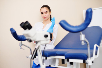 a young female gynecologist is preparing to examine a patient against the background of a gynecological chair and a microscope. Women's health