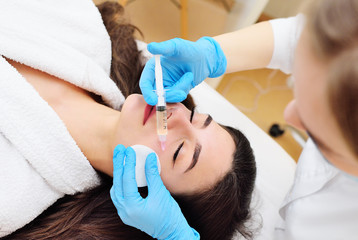 Obraz na płótnie Canvas a cosmetic surgeon performs a facial skin rejuvenation procedure using an innovative technology in which plasma enriched with platelets is injected into the patient.