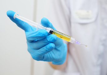 syringe with plasma in hand in a rubber glove close-up on a white background. PRP therapy