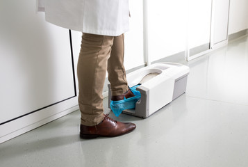 Doctor putting protective shoes on in laboratory - Powered by Adobe