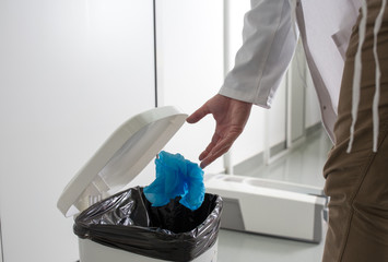 Biologist throwing overshoes in trash can
