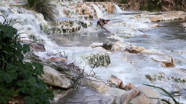 Natural spa at hot springs of Saturnia, Tuscany, Italy. Sulfur thermal baths with waterfalls, fast running warm water over rocks. Pools and riffles in a stream. Italian tourist attraction