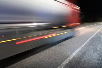 Truck with a trailer in motion on a road at night