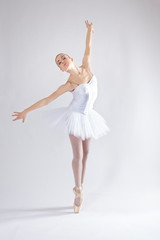 Young woman in white tutu dancing in a studio photo shoot.