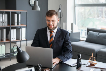 Male lawyer with laptop sitting at workplace in office