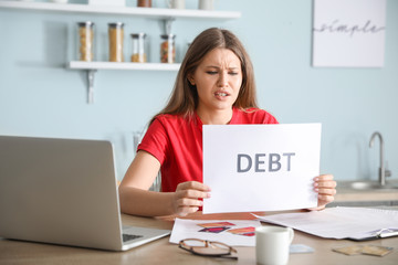 Worried young woman in debt at home