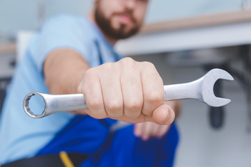 Plumber with wrench repairing sink in kitchen, closeup