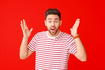 Naklejka premium Handsome surprised young man on color background