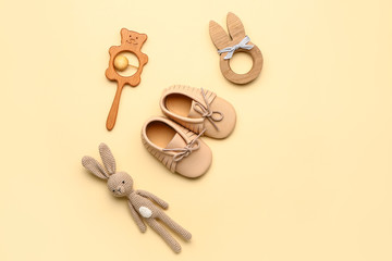 Baby booties with toys on color background