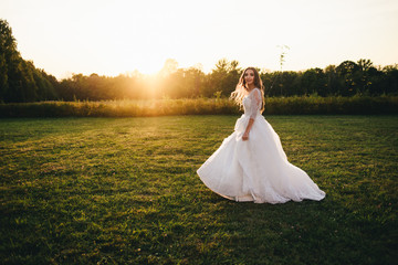 Fototapeta na wymiar Beautiful young woman in a white wedding dress and black boots at sunset is photographed.