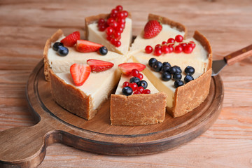 Pieces of sweet tasty cheesecake with different berries on table