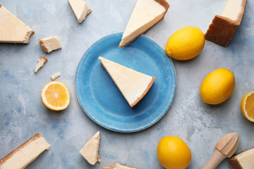 Composition with pieces of sweet tasty cheesecake and lemons on light background