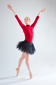 Young woman ballet dancer in red leotard and black tutu.