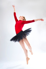 Naklejka premium Young woman ballet dancer leaping in a black tutu.