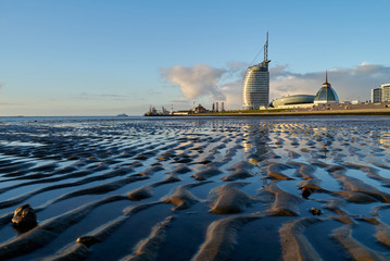 Bremerhaven, Germany - February 03, 2019: Typical buildings of the skyline seen from the mud flat at low tide with beutifully reflecting vivid blue sky in scenic late afternoon light