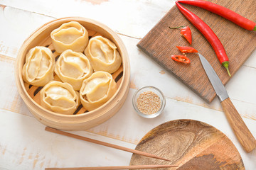 Steamer with oriental dumplings and chili pepper on table