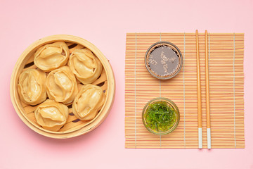 Steamer with oriental dumplings and sauce on color background