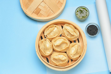 Steamer with oriental dumplings and sauce on color background