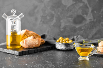 Obraz premium Tasty olive oil and bread on dark background