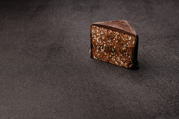 A piece of dark chocolate candy with sesame seeds and salt