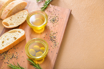 Tasty olive oil with bread on color background