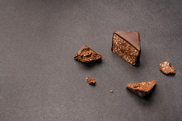 A piece of dark chocolate candy with sesame seeds and salt