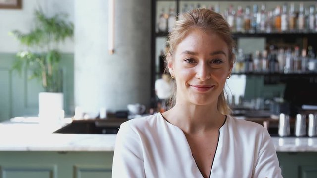 Portrait of female owner of restaurant bar standing by counter smiling and looking confident  - shot in slow motion