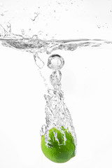 Falling of fresh lime into water against white background