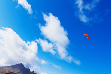 Paraglider flying over the mountains on a bright summer day. Paragliding sport concept. Copy space.