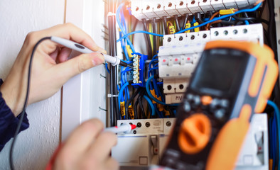 Electrician installing electric cable wires of fuse switch box. - obrazy, fototapety, plakaty