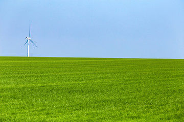 Fototapeta na wymiar One wind turbine on green meadow in sunny day