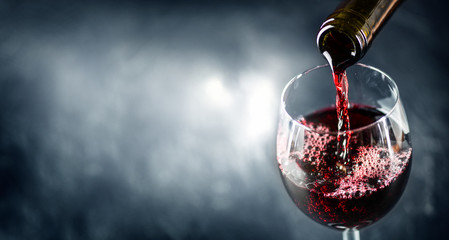 Pouring glass of red wine from a bottle in wide banner shape or copy space for text