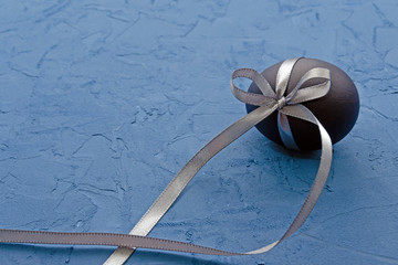 blue egg with a gray satin ribbon on a classic blue background with place for text
