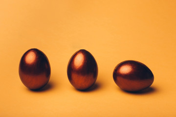 Bronze easter eggs on a yellow background.