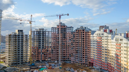 Building tower cranes and buildings under construction against classic blue sky. Construction concept.