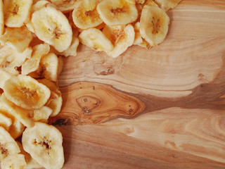 Pile of dried banana chips on a wooden board.  Copy space.