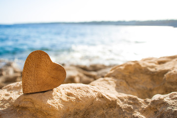 Valentine day concept, soft focus on a wooden heart, blurred sea background. Card with a wooden...