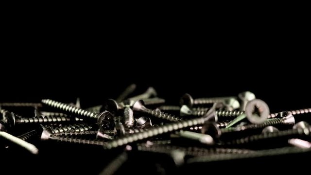 Steel screws falling with black background. Many metal screws suitable for do-it-yourself and tool construction fall in slow motion.  Close up of nails and screws that fall and bounce perfect for DIY 