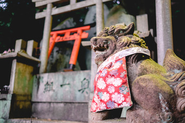 Fototapeta na wymiar Lion stone statue and torii gates at sanctuary in Fushimi Inari taisha shrine, Kyoto