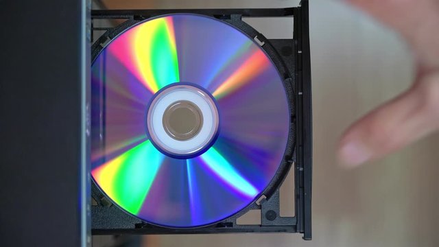 A male programmer takes out a CD-DVD from a computer drive. View from above. Outdated technology.