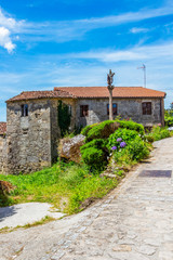 A Ponte Maceira street view with old abandoned house and stone crucifix in A Coruna Province, Galicia, Spain on the Fisterra-Muxia Way of St. James